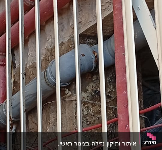 צינורות פלסטיק אפורים ואדומים על קיר
